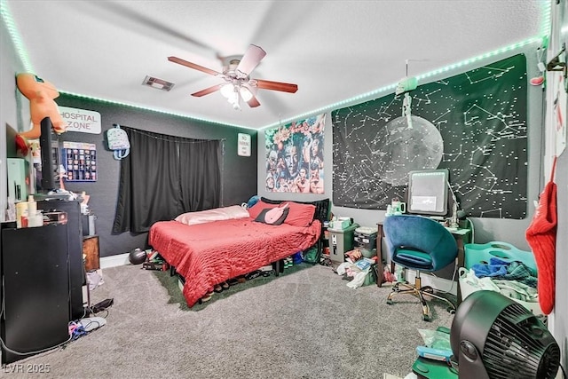 bedroom with visible vents, carpet floors, ceiling fan, and a wood stove