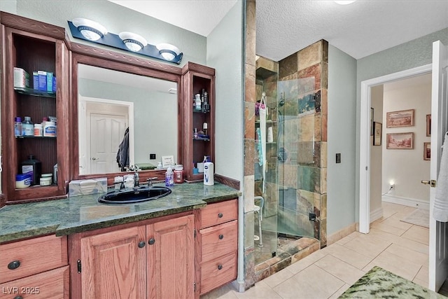 bathroom with tile patterned flooring, a shower stall, baseboards, vanity, and a textured ceiling