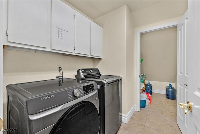 laundry room featuring light tile patterned flooring, washing machine and dryer, cabinet space, and baseboards