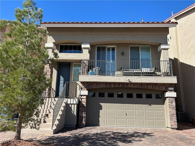 view of front of home featuring a garage, decorative driveway, stairway, and stucco siding