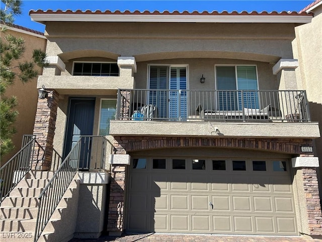 view of front of property featuring an attached garage, a tiled roof, and stucco siding