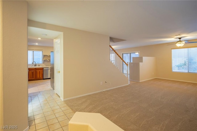 empty room featuring stairs, a healthy amount of sunlight, light tile patterned flooring, and light colored carpet