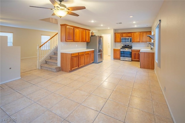 kitchen with light tile patterned floors, stainless steel appliances, brown cabinetry, and light countertops