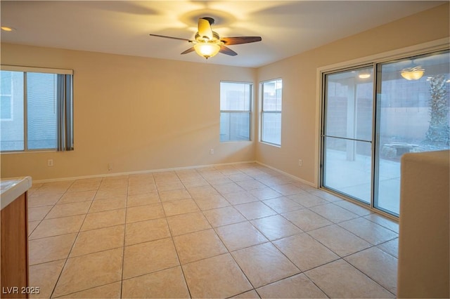 unfurnished room with a ceiling fan, light tile patterned flooring, and baseboards