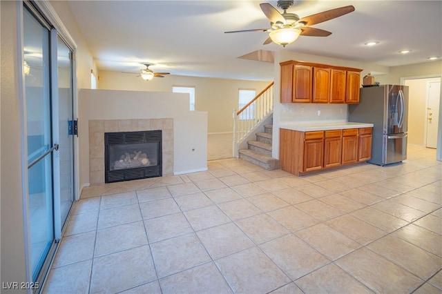 kitchen with light tile patterned floors, open floor plan, light countertops, stainless steel refrigerator with ice dispenser, and brown cabinetry