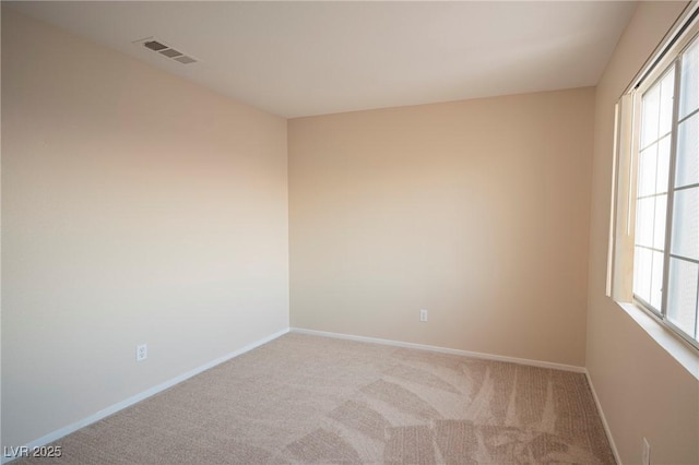 empty room featuring a healthy amount of sunlight, carpet floors, baseboards, and visible vents