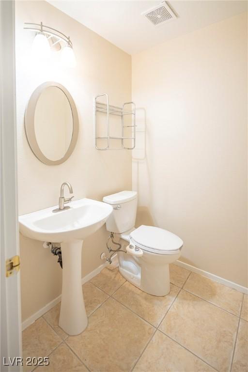 half bath with tile patterned flooring, baseboards, visible vents, and toilet