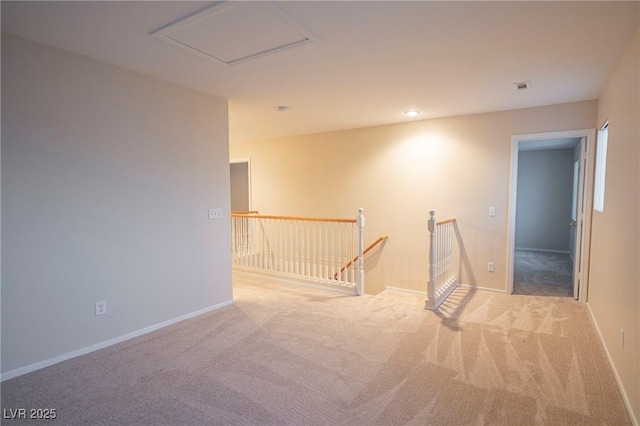 empty room with attic access, carpet, and baseboards