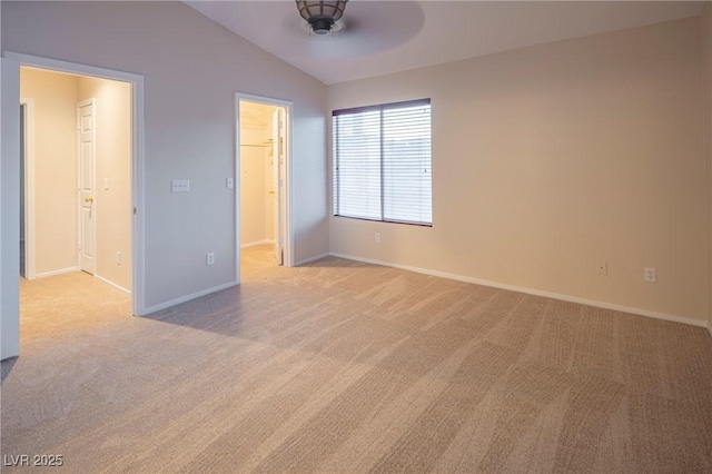 unfurnished bedroom with lofted ceiling, light colored carpet, baseboards, a spacious closet, and a closet