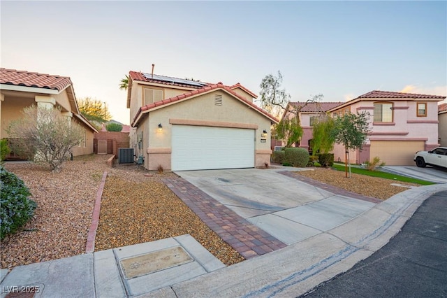 mediterranean / spanish-style home with concrete driveway, an attached garage, cooling unit, and stucco siding