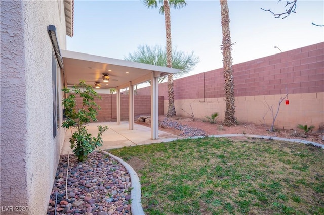 view of yard featuring a patio area, a fenced backyard, and a ceiling fan