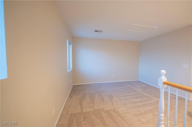 unfurnished room featuring attic access, visible vents, baseboards, and light colored carpet