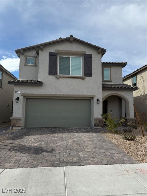 view of front of home with an attached garage, a tile roof, decorative driveway, and stucco siding