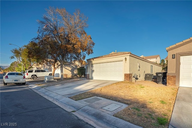 view of front facade with a tile roof, driveway, an attached garage, and stucco siding