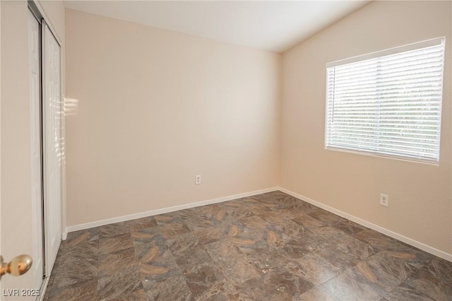 unfurnished bedroom featuring lofted ceiling, a closet, and baseboards