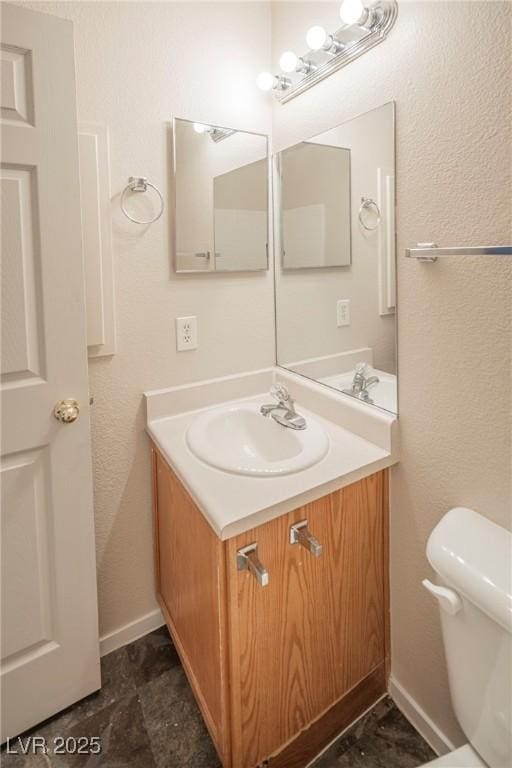 bathroom with baseboards, vanity, and toilet