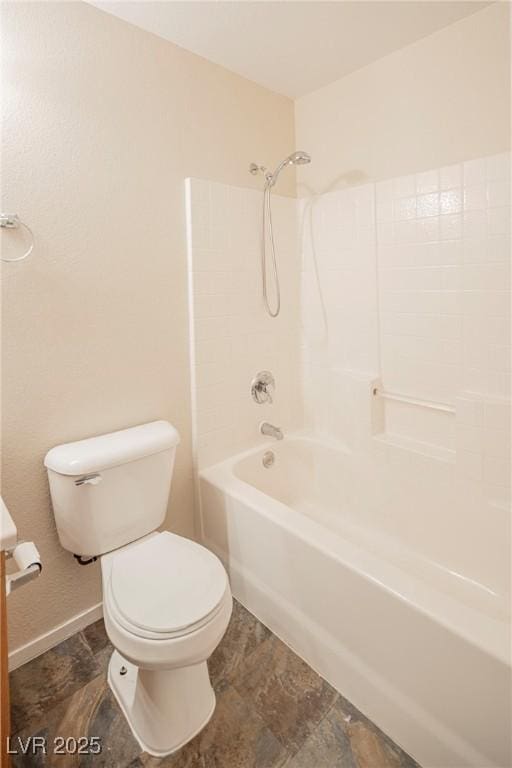 bathroom featuring bathing tub / shower combination, toilet, and baseboards