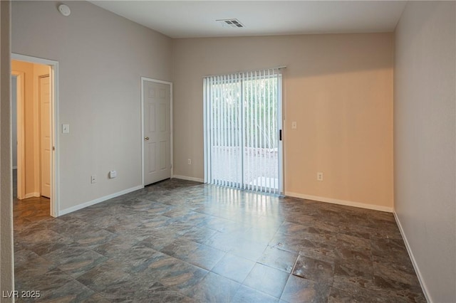 spare room with lofted ceiling, stone finish floor, visible vents, and baseboards