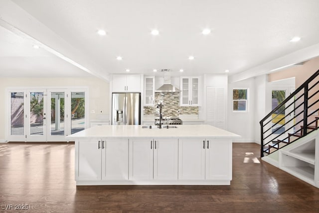 kitchen with decorative backsplash, stainless steel fridge with ice dispenser, a spacious island, light countertops, and white cabinetry