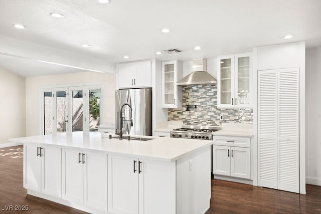 kitchen with a kitchen island with sink, dark wood-type flooring, white cabinets, stainless steel refrigerator with ice dispenser, and wall chimney exhaust hood