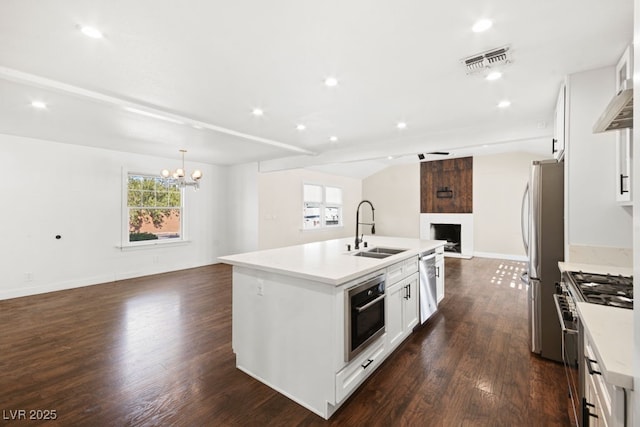 kitchen with visible vents, open floor plan, stainless steel appliances, a fireplace, and a sink