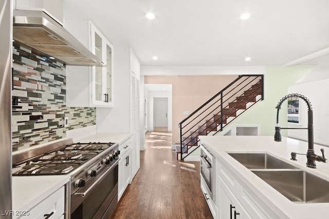 kitchen featuring extractor fan, dark wood-style flooring, a sink, backsplash, and stainless steel range with gas stovetop