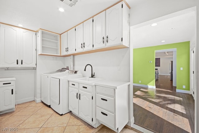 washroom featuring cabinet space, visible vents, a sink, separate washer and dryer, and baseboards