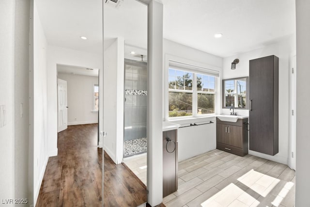 bathroom with recessed lighting, a stall shower, vanity, wood finished floors, and baseboards