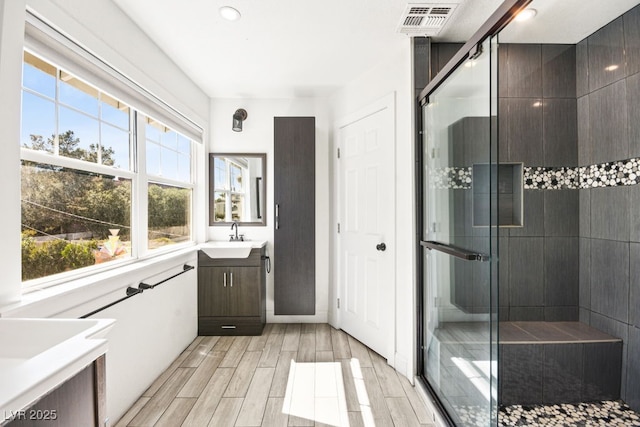 full bathroom with a stall shower, visible vents, vanity, and wood finish floors