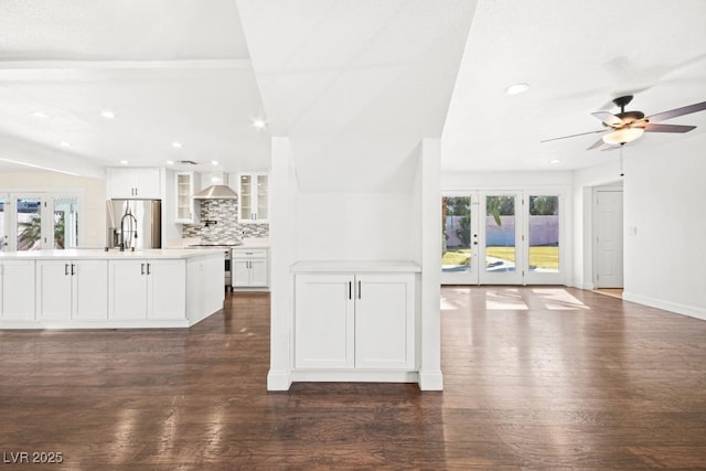 kitchen with stainless steel appliances, wall chimney exhaust hood, backsplash, and dark wood finished floors