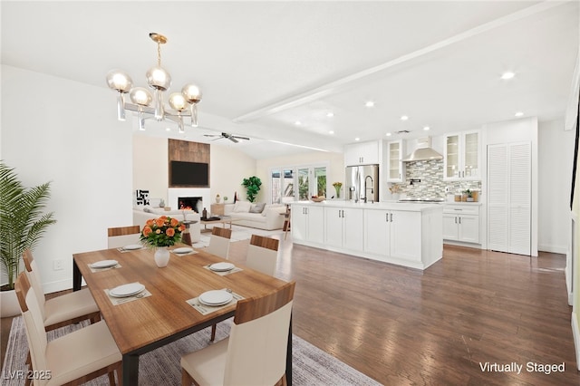 dining room with vaulted ceiling with beams, recessed lighting, a notable chandelier, a fireplace, and wood finished floors