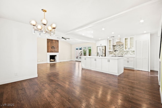 unfurnished living room featuring a fireplace with raised hearth, lofted ceiling with beams, dark wood-type flooring, a sink, and baseboards