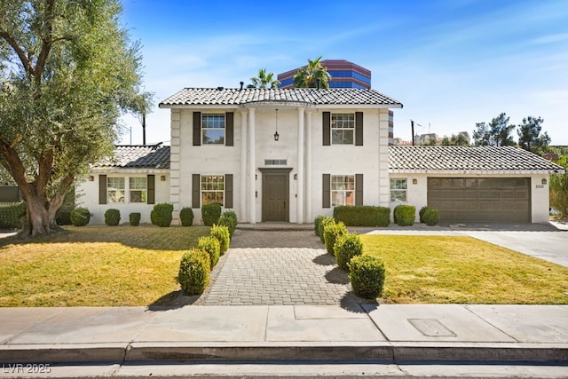 view of front of property with concrete driveway, a front lawn, an attached garage, and stucco siding