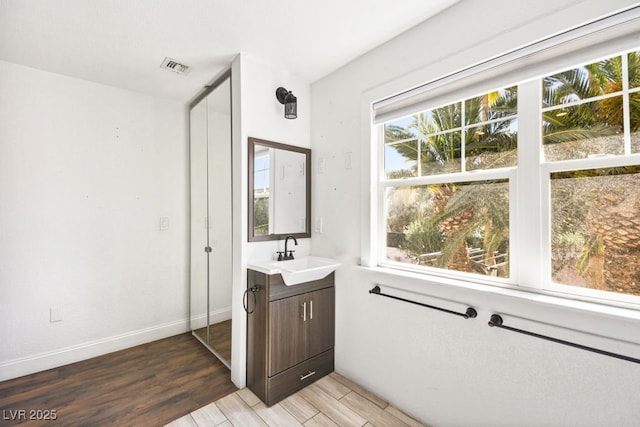 bathroom with vanity, wood finished floors, visible vents, and baseboards