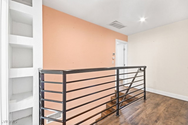 hallway featuring baseboards, visible vents, an upstairs landing, and wood finished floors