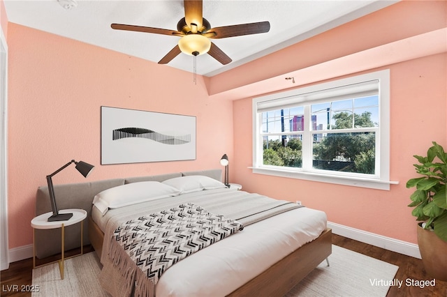 bedroom with ceiling fan, baseboards, and wood finished floors