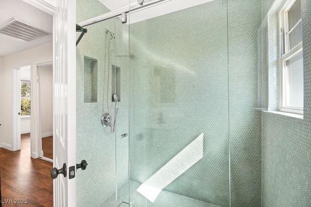 bathroom with visible vents, a tile shower, baseboards, and wood finished floors