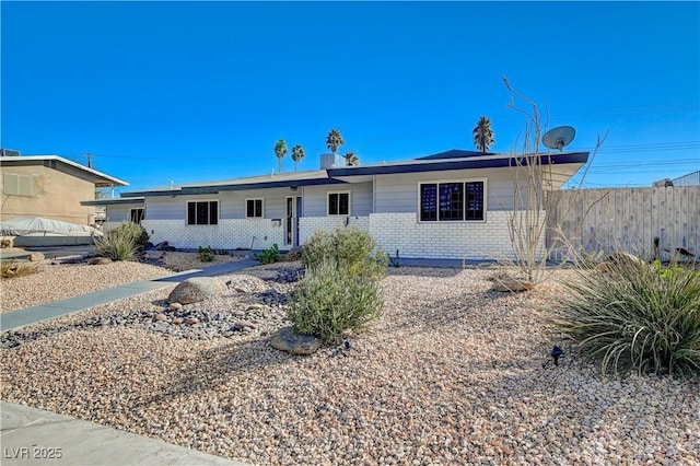 ranch-style home featuring brick siding and fence