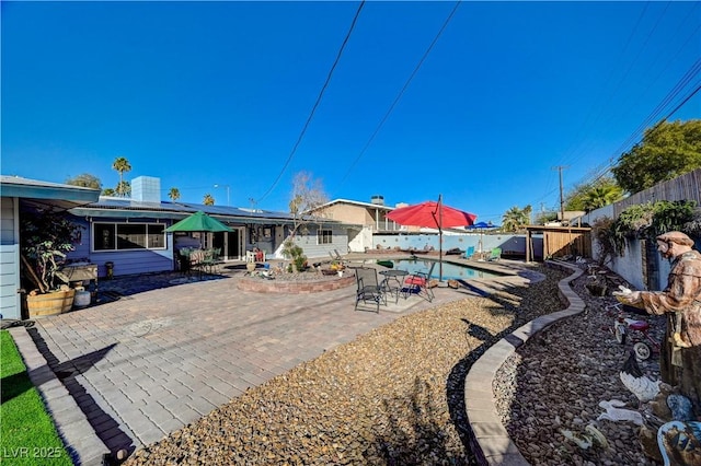 rear view of house featuring solar panels, a patio area, a fenced in pool, and a fenced backyard