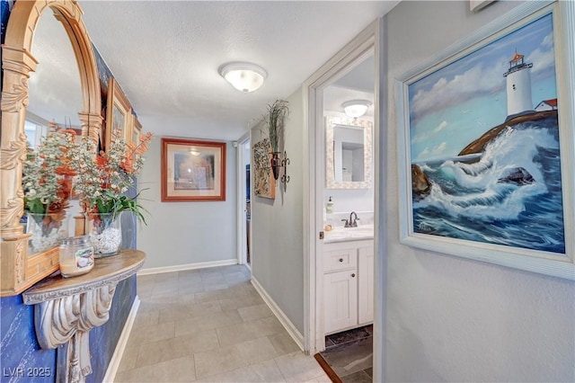 corridor with a sink, baseboards, and a textured ceiling