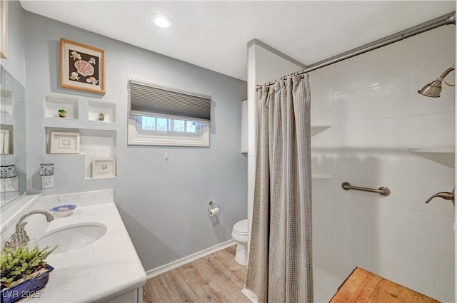 bathroom featuring baseboards, toilet, a shower with curtain, wood finished floors, and vanity