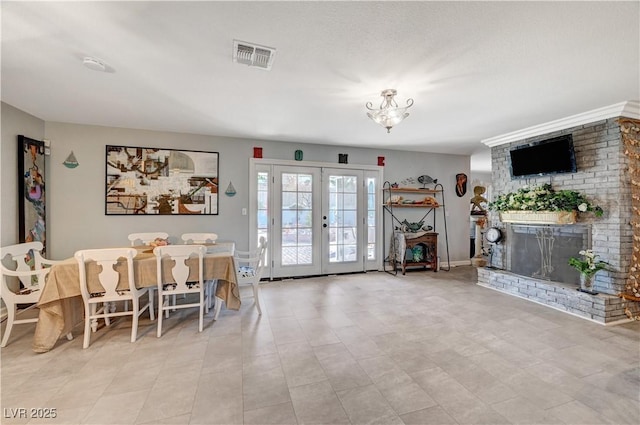 interior space with french doors, visible vents, a chandelier, and a fireplace