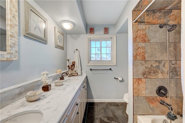 full bath with baseboards, double vanity, a sink, bathtub / shower combination, and toilet