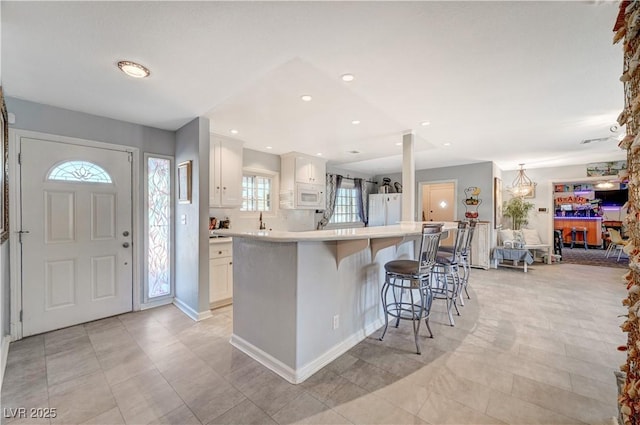 kitchen with white cabinetry, white appliances, light countertops, and a breakfast bar