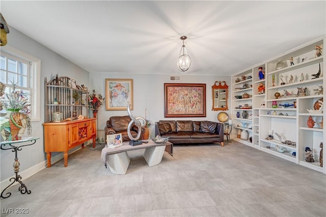 living area with a notable chandelier, visible vents, baseboards, and built in features