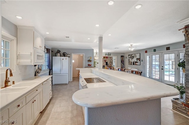 kitchen with white appliances, a sink, light countertops, white cabinets, and french doors