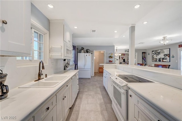 kitchen featuring visible vents, a sink, white appliances, white cabinets, and light countertops