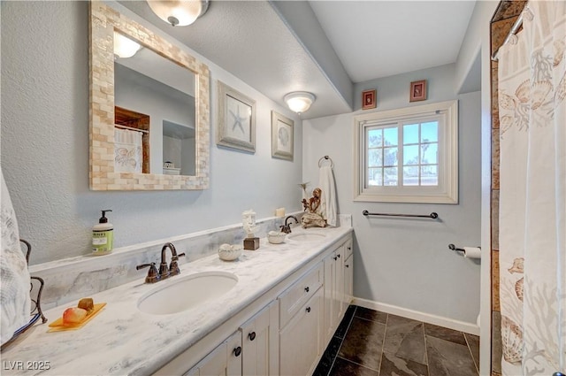 full bath featuring double vanity, baseboards, and a sink