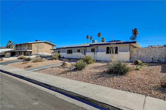 ranch-style home featuring brick siding and fence