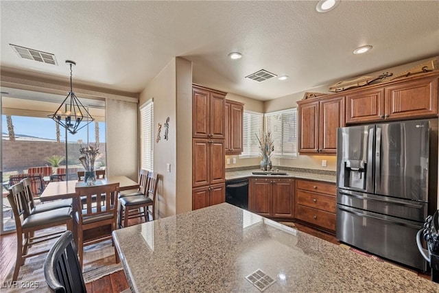 kitchen with black dishwasher, brown cabinetry, stainless steel refrigerator with ice dispenser, and visible vents